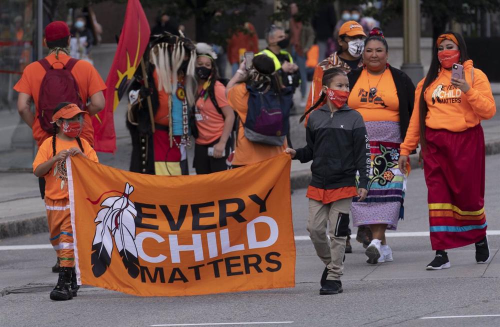 Archivo - Niños indígenas llevan una bandera mientras marchan durante las ceremonias del Día Nacional de la Verdad y la Reconciliación en la Colina del Parlamento. Archivo