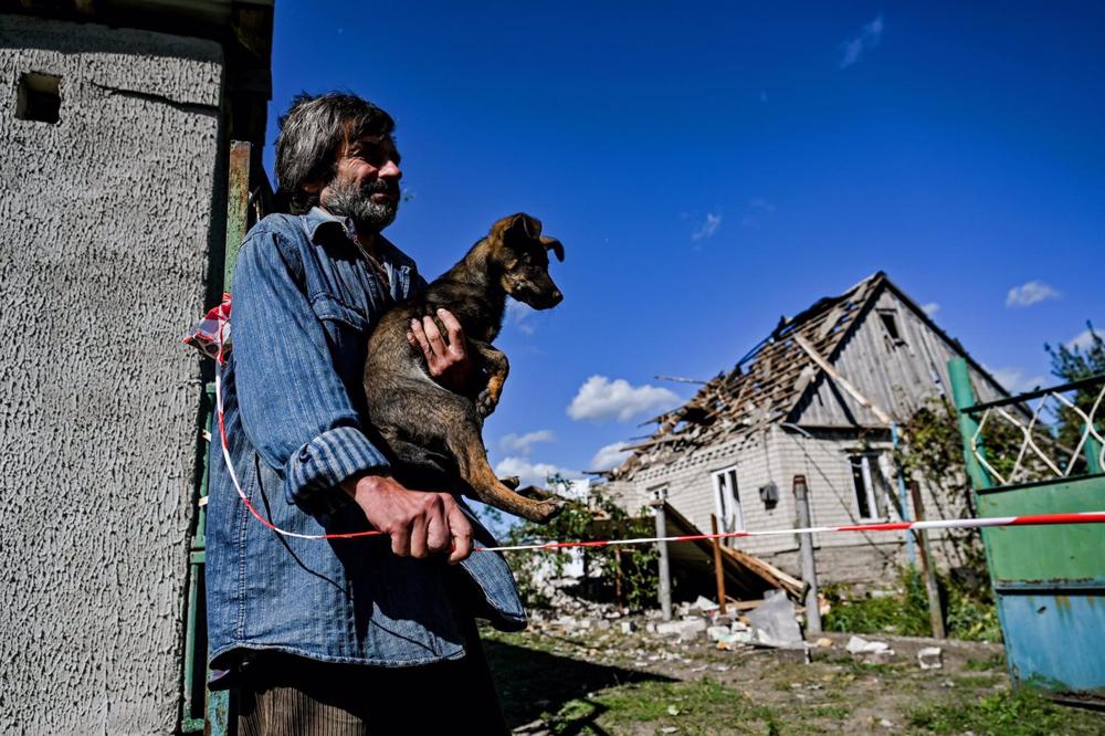 File - A man and his dog in front of houses affected by a falling Russian missile in Zaporiyia. File