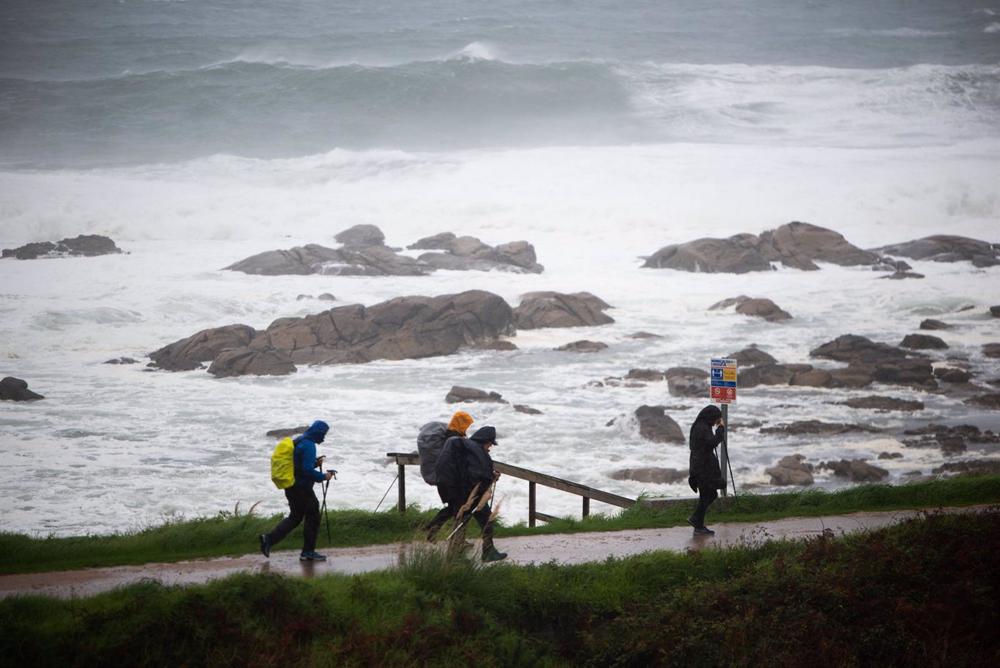 Varios peregrinos realizan el Camino de Santiago, a pesar del temporal, en la zona de Santa Maria de Oia hasta Cabo Silleiro, a 20 de octubre de 2022, en Pontevedra, Galicia, (España). Varios