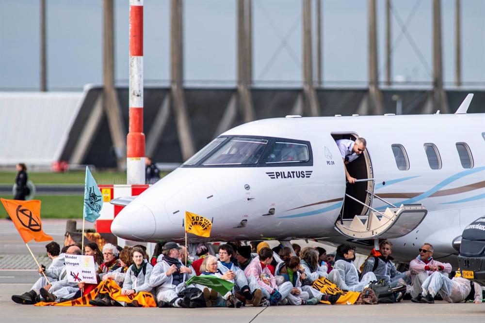 Climate activists under a private plane at Amsterdam-Schiphol Airport Climate