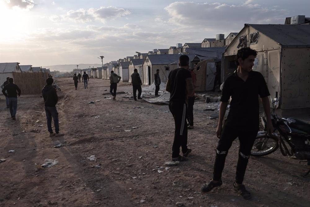 Un gruppo di persone ispeziona i danni dopo un attacco a un campo per sfollati nella provincia di Idlib, nella Siria nord-occidentale. Un