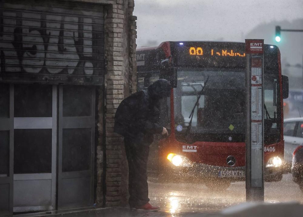 Una persona se protege de la lluvia con la capucha de su chaqueta, en València Una