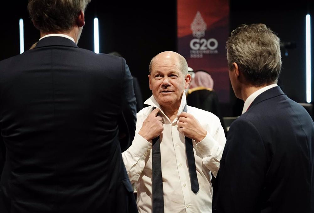 German Chancellor Olaf Scholz puts on his tie. German