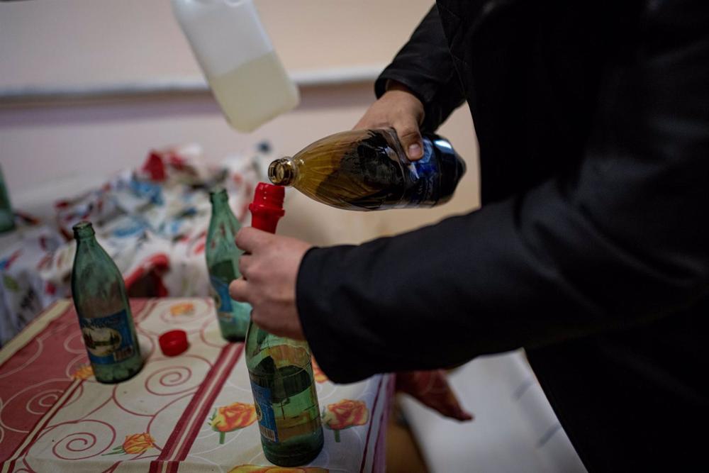 Ficheiro - Ficheiro imagem de um homem a fazer um cocktail Molotov. Ficheiro