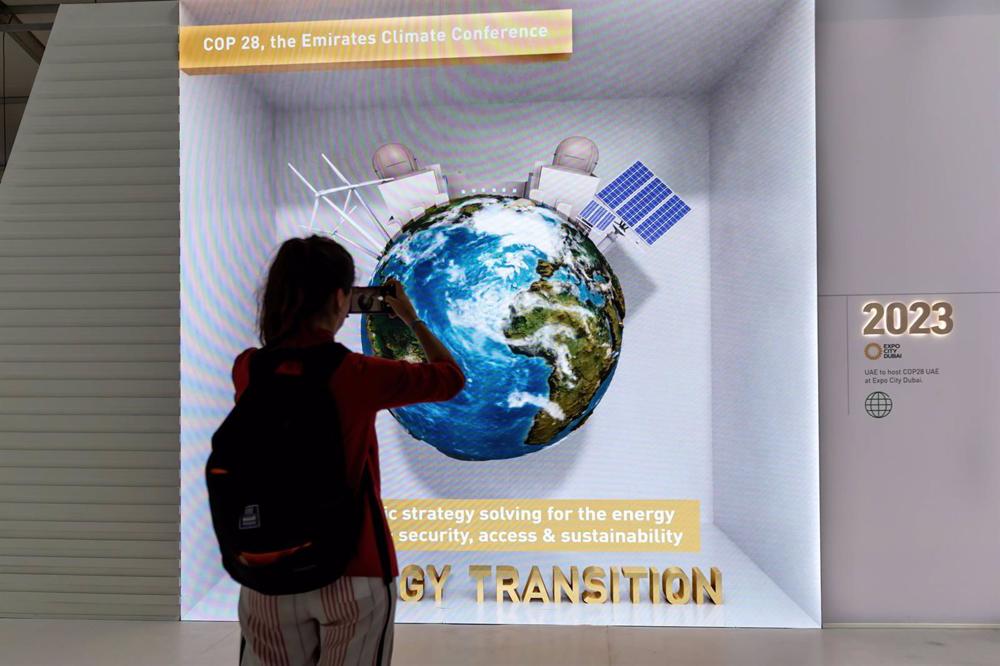 18 November 2022, Egypt, Sharm El-Sheikh: A woman takes a photograph in United Arab Emirates Pavilion which advertises next's year, 2023 conference in Dubai on the final day of the 2022 United Nations Climate Change Conference COP27. Photo: Dominika Zarzy 18