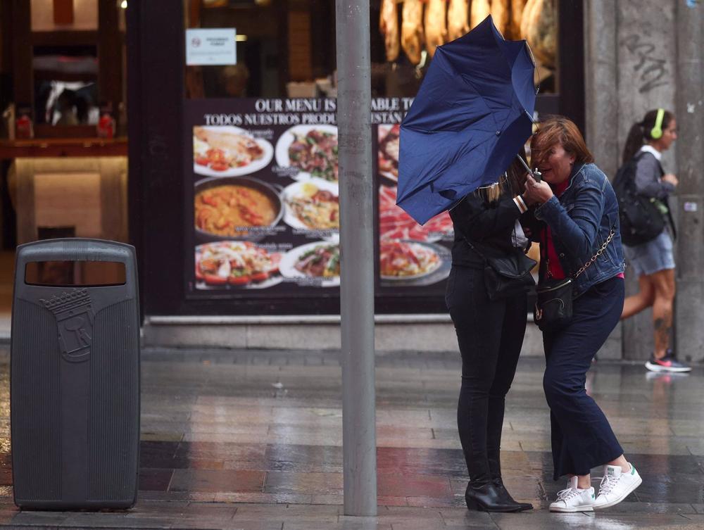 Archivo - Dos chicas intentan controlar su paraguas, en la calle Gran Vía, a 20 de octubre, en Madrid (España). Archivo