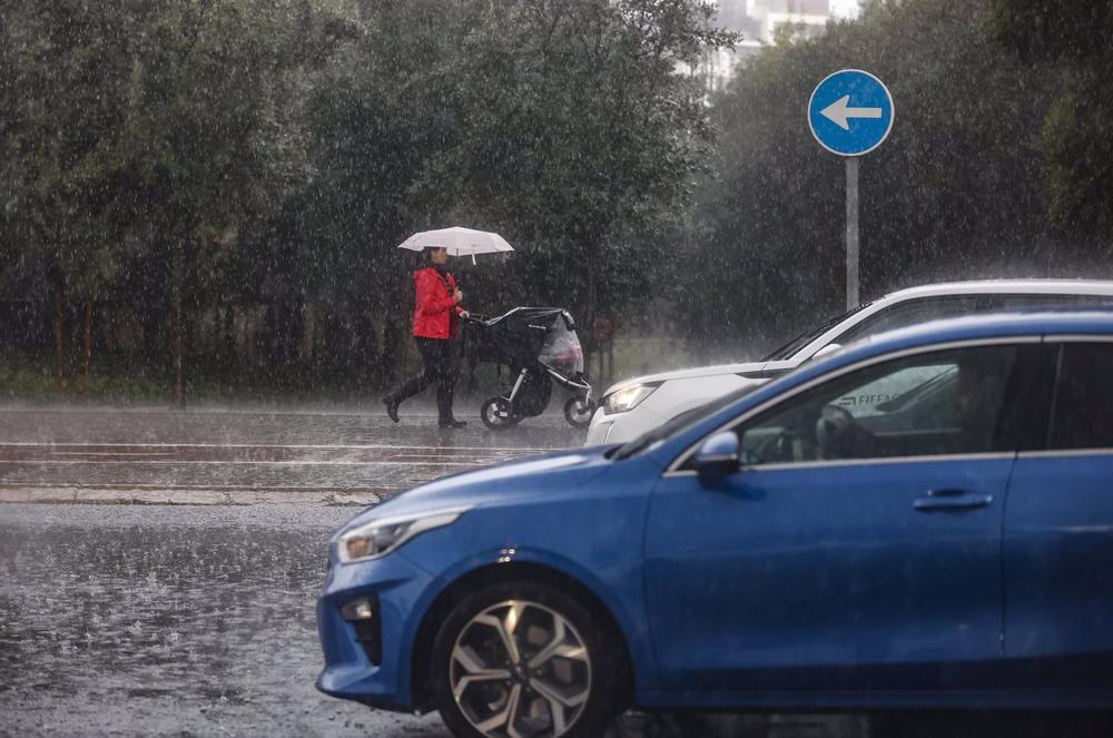 Una mujer lleva un carrito de bebé mientras se protege de la lluvia con un paraguas, a 11 de noviembre de 2022, en Valencia, Comunidad Valenciana (España). La Agencia Estatal de Meteorología (Aemet) mantiene el aviso de nivel amarillo por lluvias en el l Una
