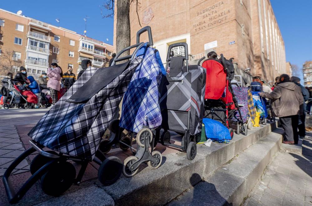 Archivo - Varias personas hacen cola para recibir alimentos. Archivo