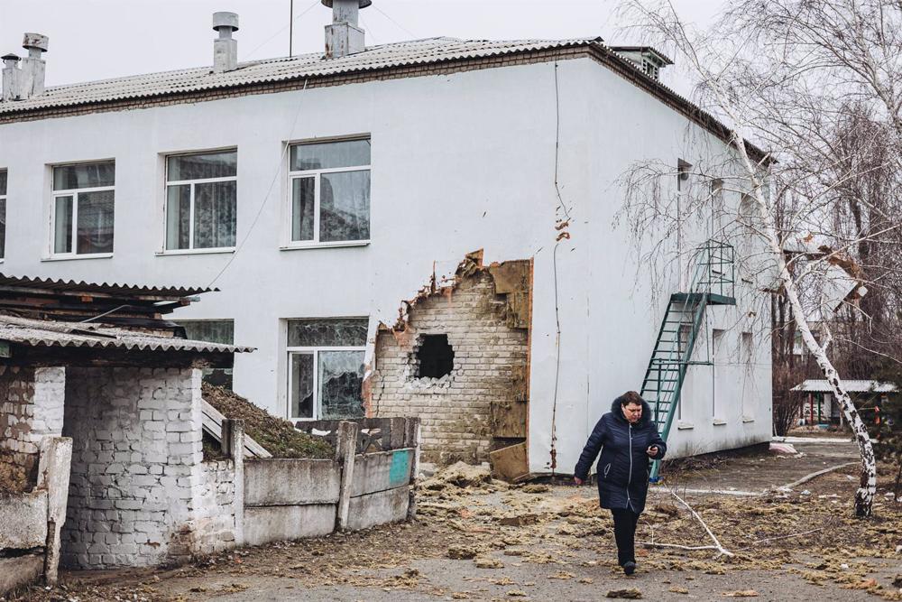 File - A woman walks in front of the kindergarten where a shell hit today, February 17, 2022, in Stanitsa Luganska, Lugansk Oblast, Ukraine. File