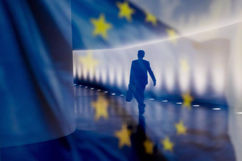 File - Reflection of a person next to a European Union (EU) flag. File
