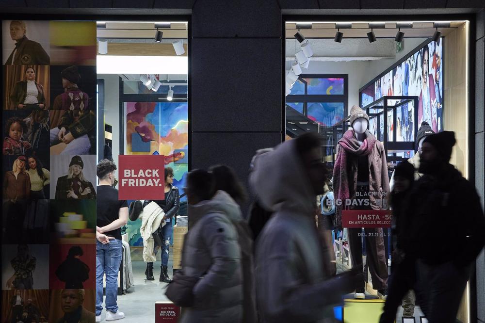 Varias personas pasan por delante de los comercios que anuncian los descuentos del Black Friday, Varias