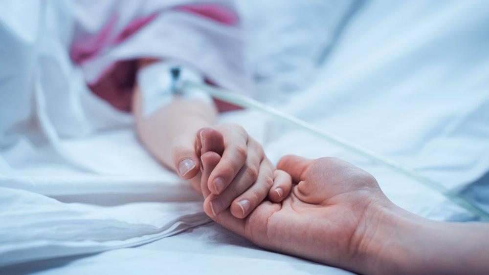 Un adulto coge la mano de un niño hospitalizado. Un