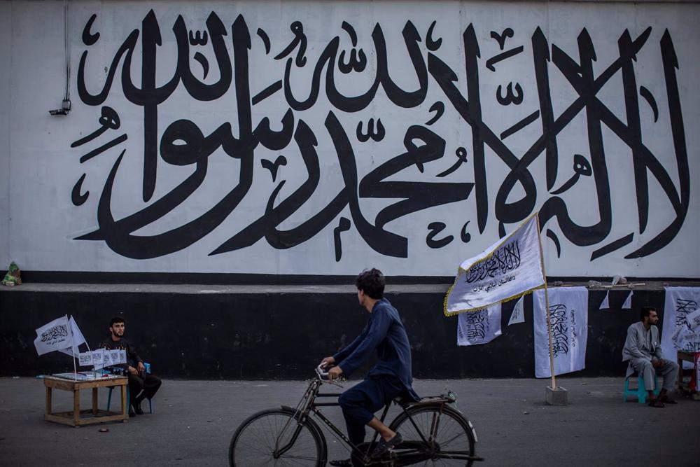 File - A man sells Taliban flags in front of the wall of the former US Embassy in Afghanistan's capital Kabul, now covered with a religious mural. File