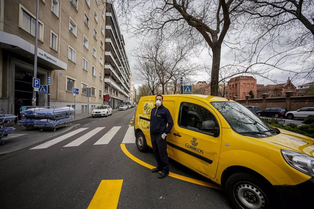 Archivo - Un repartidor de Correos al lado de su vehículo Archivo