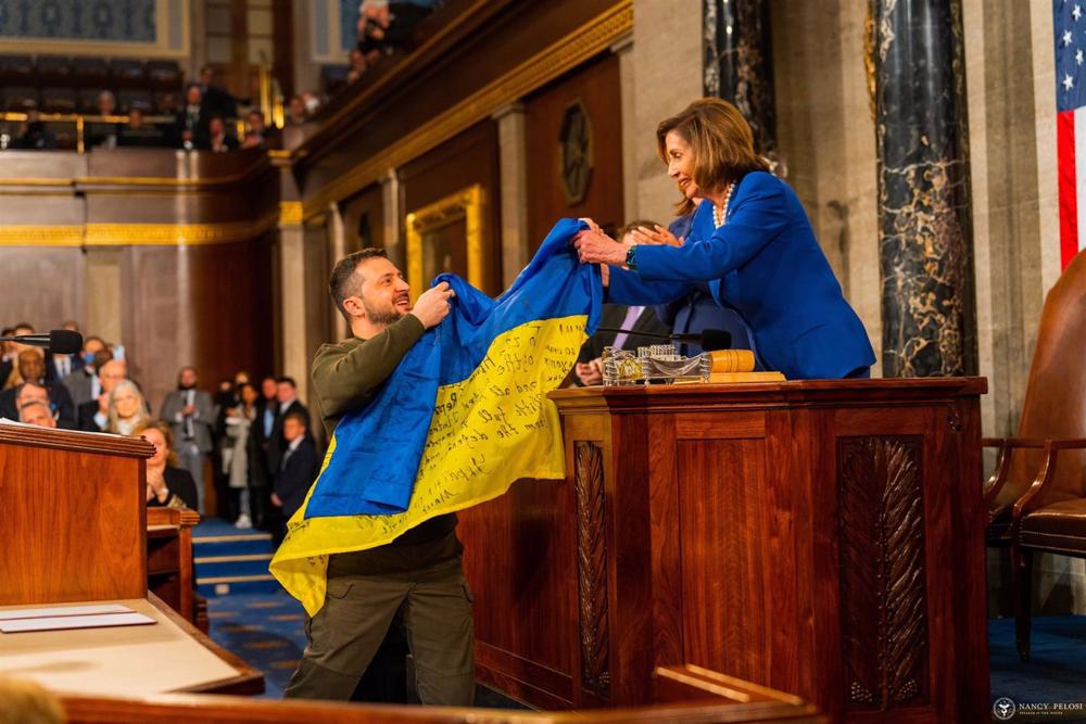 El presidente de Ucrania, Volodimir Zelenski, entrega a la presidenta de la Cámara de Representantes de Estados Unidos, Nancy Pelosi, una bandera de Ucrania El