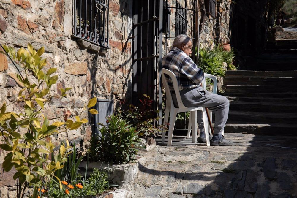 Archivo - Un hombre sentado en un silla en una de las calles empedradas de Patones de Arriba Archivo