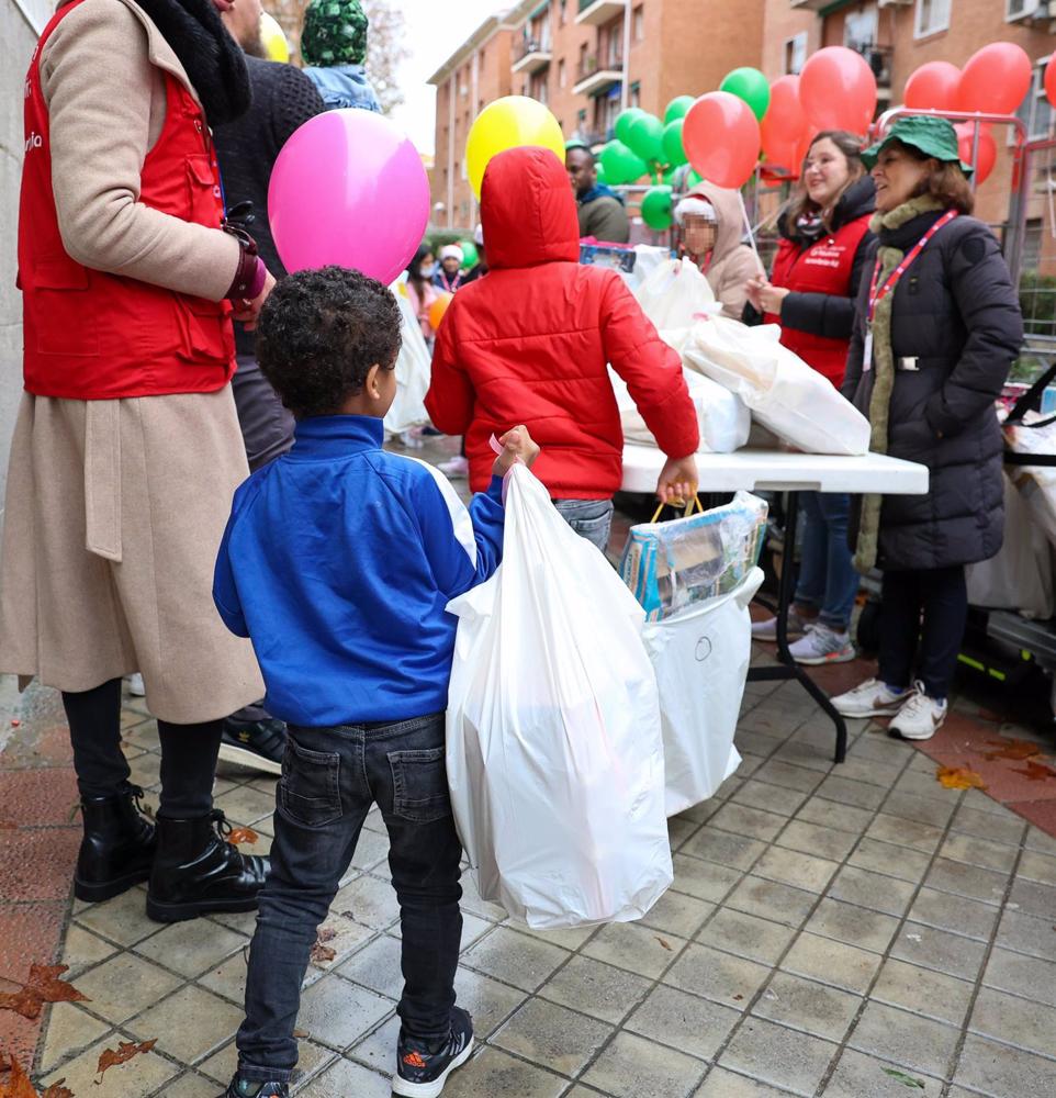 Un niño sujeta una bolsa con regalos en el reparto de regalos de la Fundación Madrina a 500 niños de familias vulnerables, en la Plaza de San Amaro, a 23 de diciembre de 2022, en Madrid (España). Un
