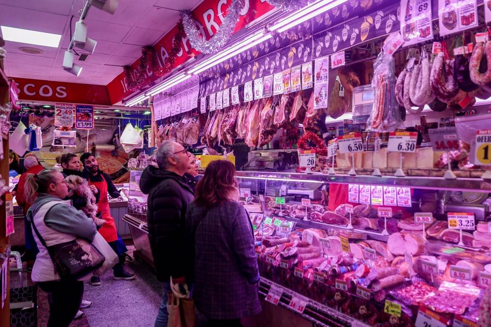Varias personas esperan su turno en la charcutería para realizar sus últimas compras en la tienda de comestibles Varias