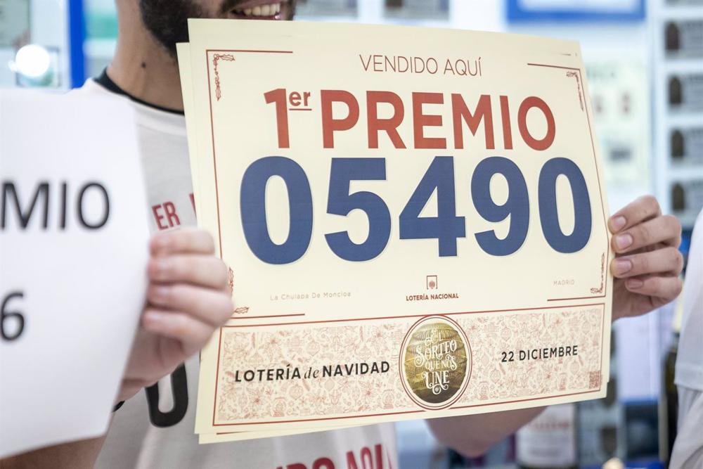 Un empleado de la administración situada en el intercambiador de Moncloa llamada 'La chulapa de Moncloa' celebra que han vendido parte del número 5490 correspondiente al 'Gordo' del Sorteo Extraordinario de la Lotería de Navidad, a 22 de diciembre de 2022 Un