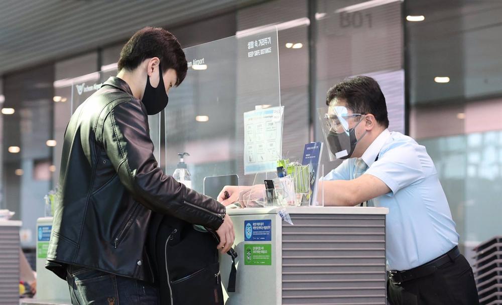 Dossier - Un passager montre un certificat de résultat négatif au test de dépistage du coronavirus à un employé de l'aéroport international d'Incheon en Corée du Sud. Dossier