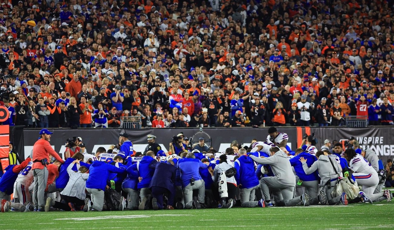 Buffalo Bills players kneel in a circle on the ground. - BUFFALO BILLS Buffalo