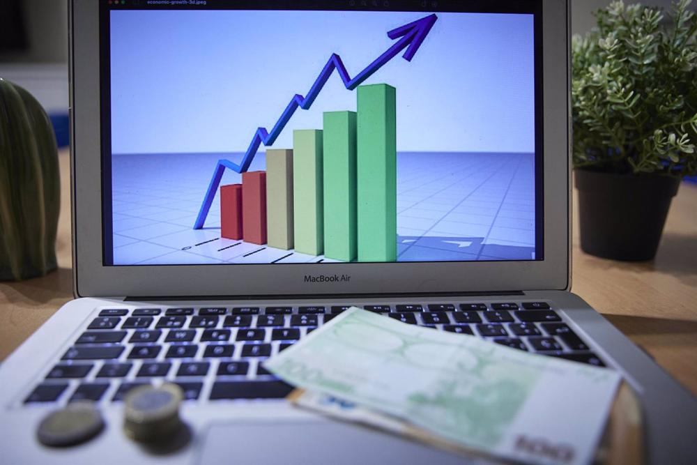 Archivo - Un gráfico en un ordenador portátil con billetes y monedas, a 4 de enero de 2022, en Madrid, (España). Archivo