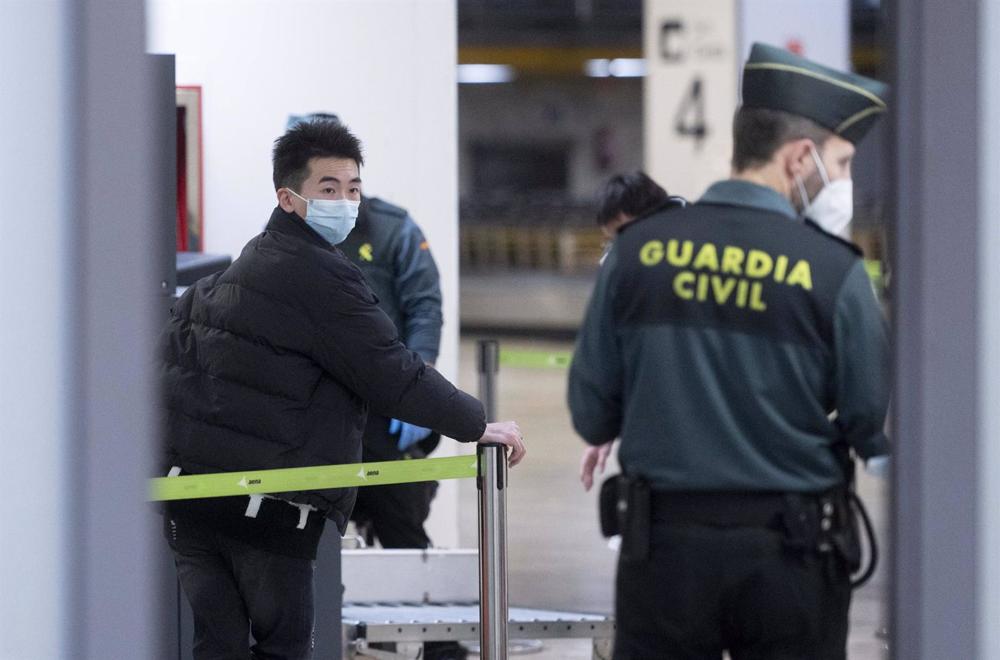Un agente della Guradia Civil con un passeggero in arrivo all'aeroporto Adolfo Suárez Madrid-Barajas da un volo proveniente da Chongqing (Cina), il 3 gennaio 2023, a Madrid (Spagna). Un