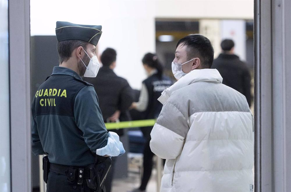 A Guradia Civil agent with a passenger arriving at Adolfo Suarez Madrid-Barajas airport from a flight from Chongqing, China, on January 3, 2023, in Madrid, Spain. A
