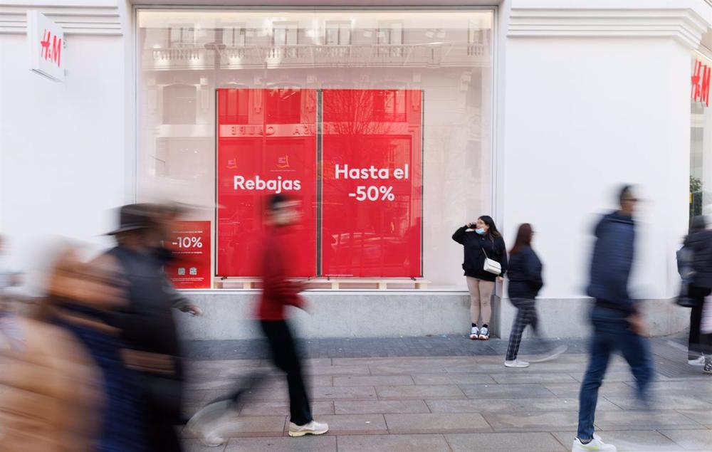 Varias personas caminan frente a una tienda de H&M con el cartel de rebajas Varias