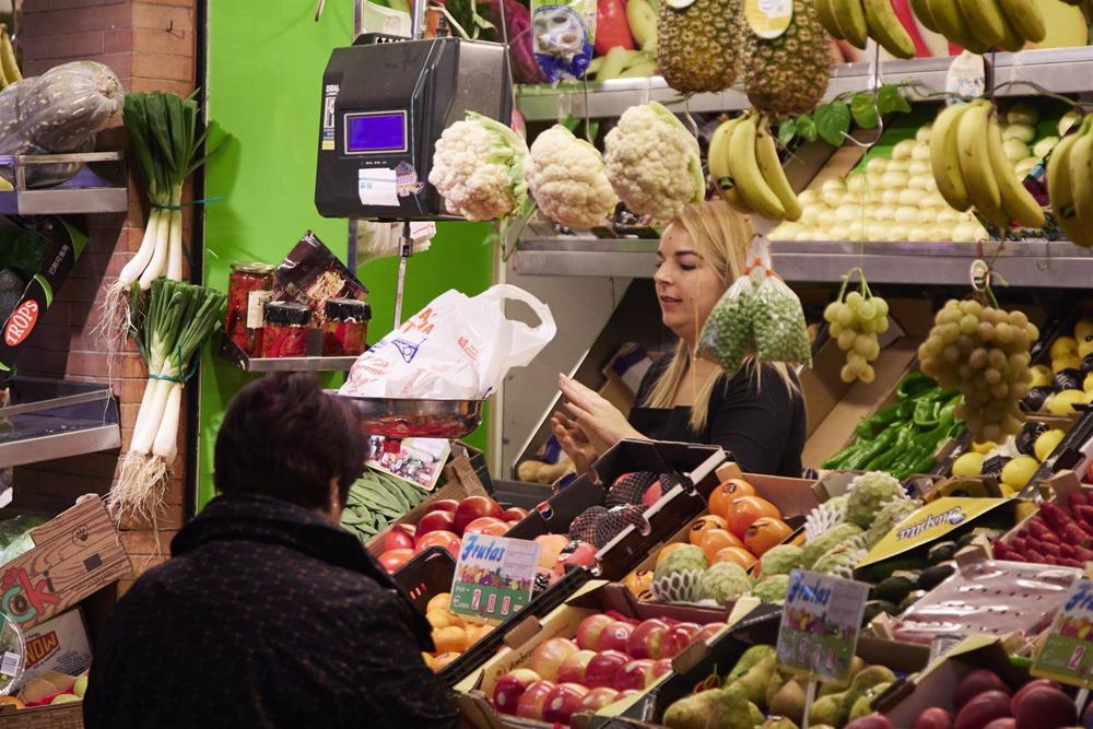 Un dependienta pesa una bolsa con frutas en las compras en los Mercados de Abastos antes de la Navidad , a 23 de diciembre de 2022 en Sevilla (Andalucía, España). Un