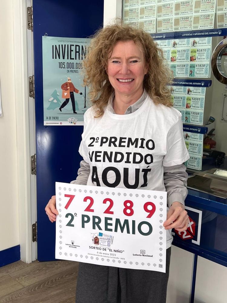 La responsable del despacho de lotería de Guillena muestra el cartel con el número del segundo premio del sorteo del Niño. La