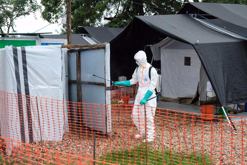 Dossier - Un ouvrier désinfecte un centre d'isolation contre le virus Ebola dans le district de Mubende, en Ouganda. Dossier