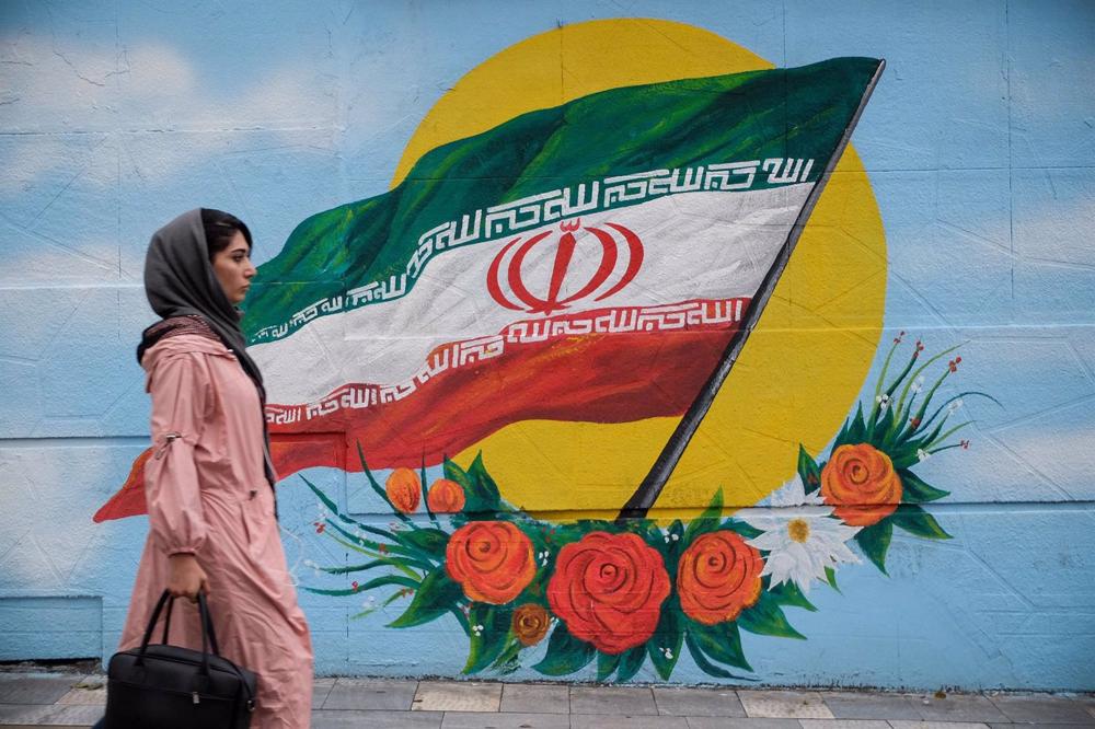 Dossier - Une femme passe devant une peinture murale du drapeau iranien dans une rue de Téhéran. Dossier