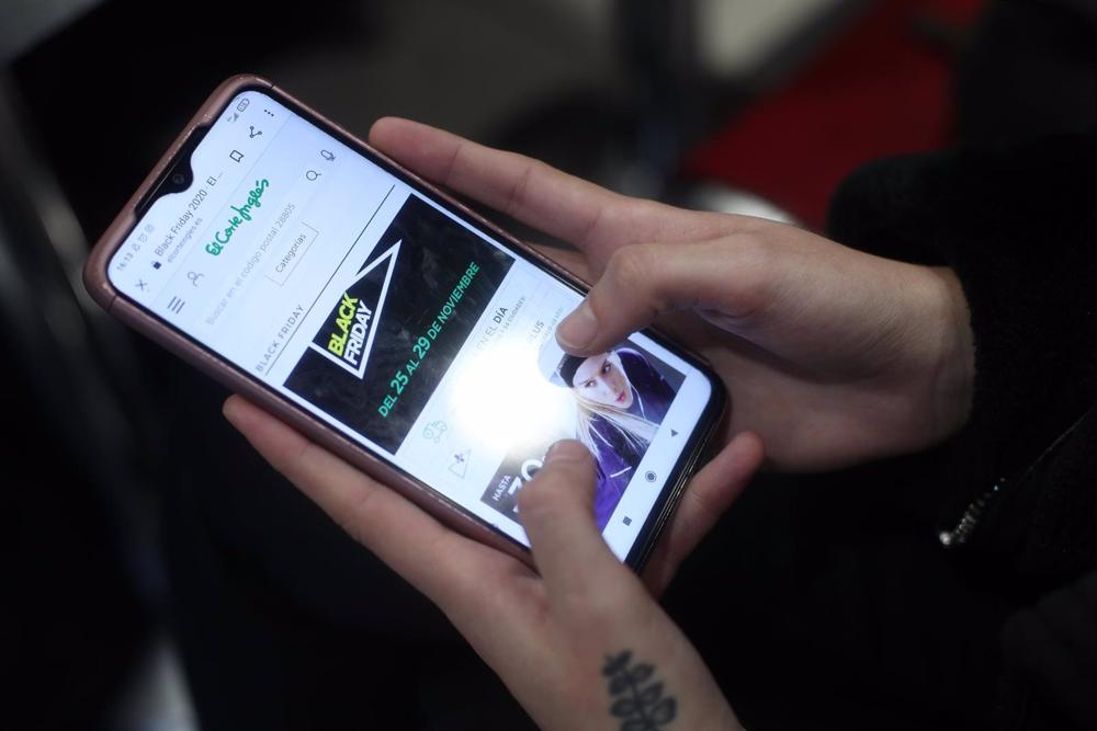 Archivo - Una joven consulta las ofertas de Black Friday de un comercio en su móvil, Archivo