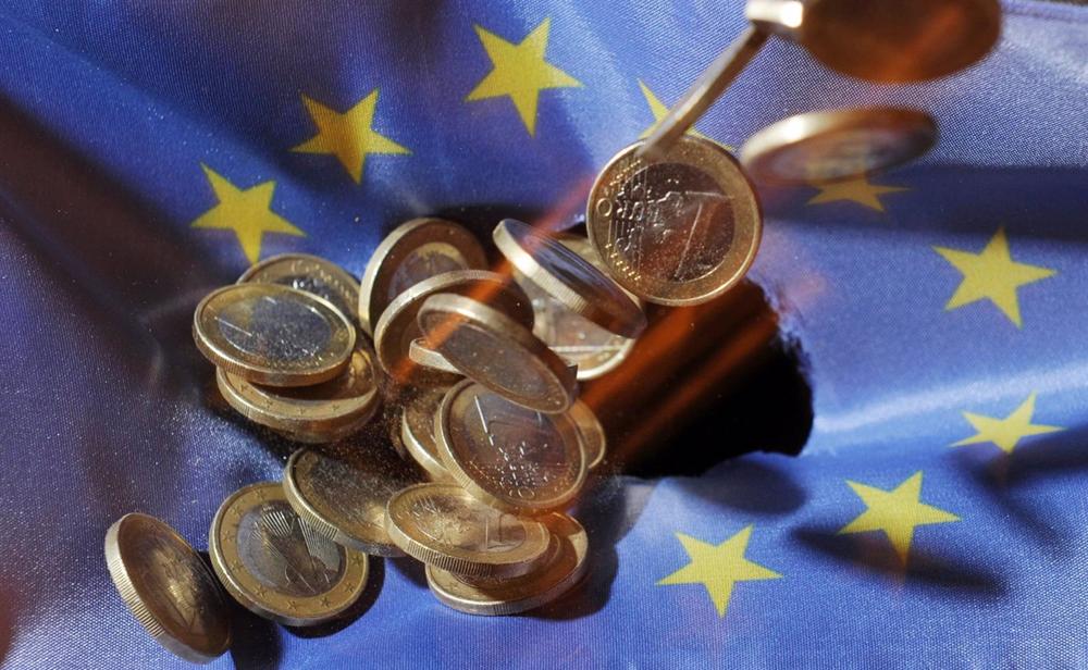 Archivo - Monedas de euro sobre la bandera de la Unión Europea. Archivo