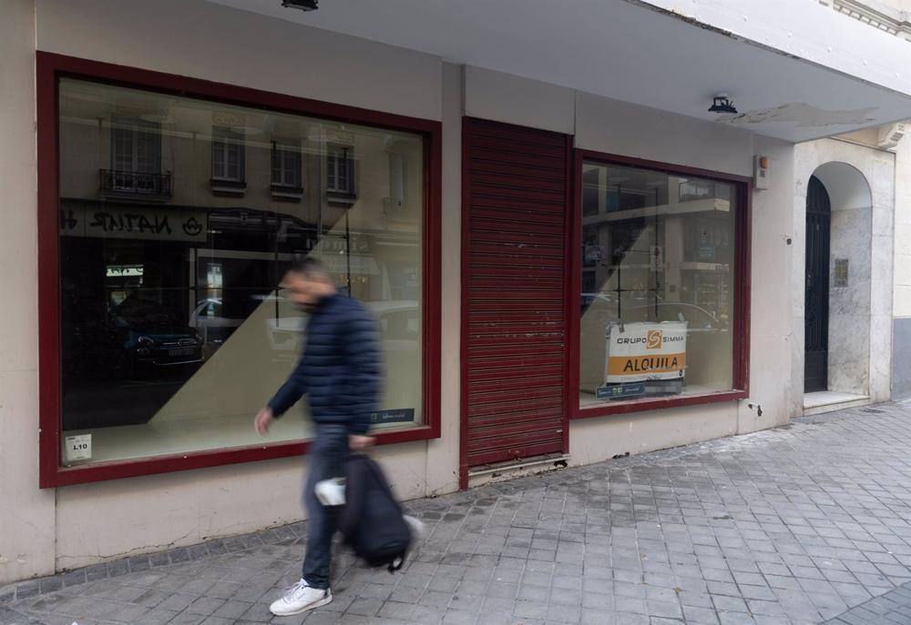 Archivo - Una persona pasa por delante de un comercio cerrado, en Madrid (España) Archivo