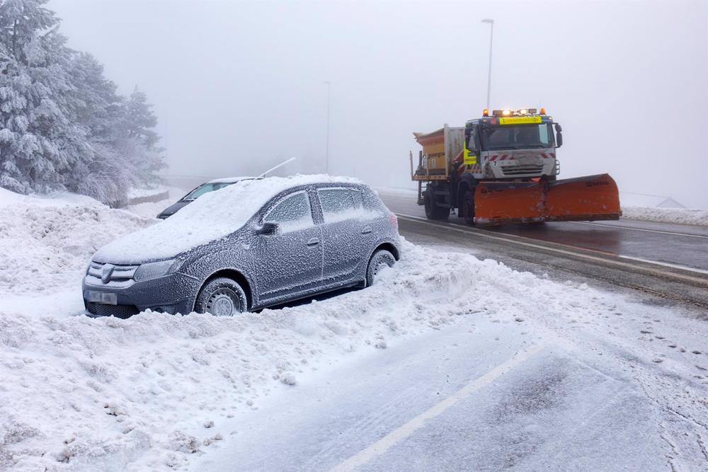 Un coche cubierto de nieve y una máquina quitanieves en la carretera de acceso al Puerto de Navacerrada, a 19 de enero de 2023, en Navacerrada, Madrid (España). La Agencia de Seguridad y Emergencias de la Comunidad de Madrid (ASEM 112) ha activado la situ Un