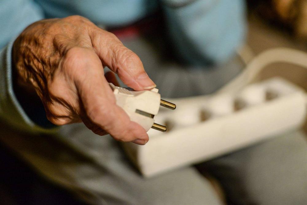 Archivo - Un anciano sostiene un enchufe en su mano. Archivo