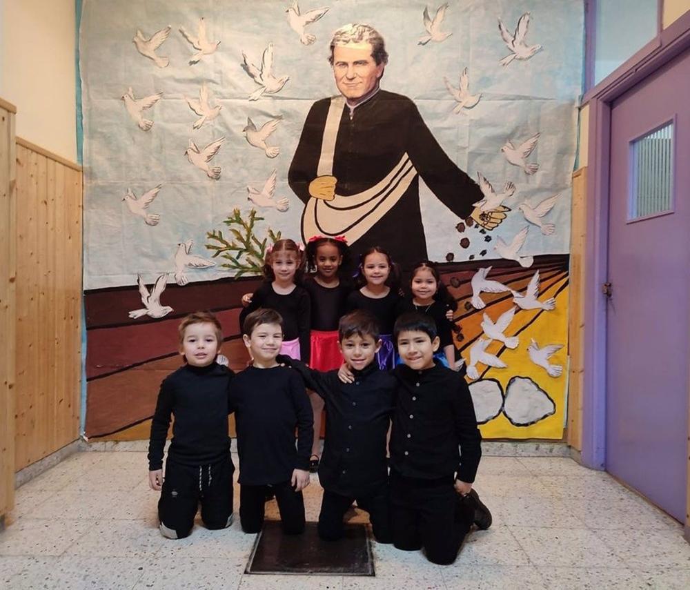 Un grupo de niños junto a la imagen de San Juan Bosco. Un
