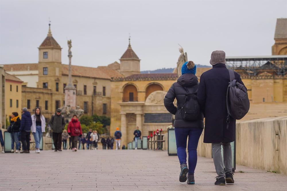 Transeúntes y turistas por el famoso puente de San Rafael con vistas a la Mezquita en el primer día intenso de frío a 16 de enero de 2023 en Córdoba (Andalucía, España). Transeúntes