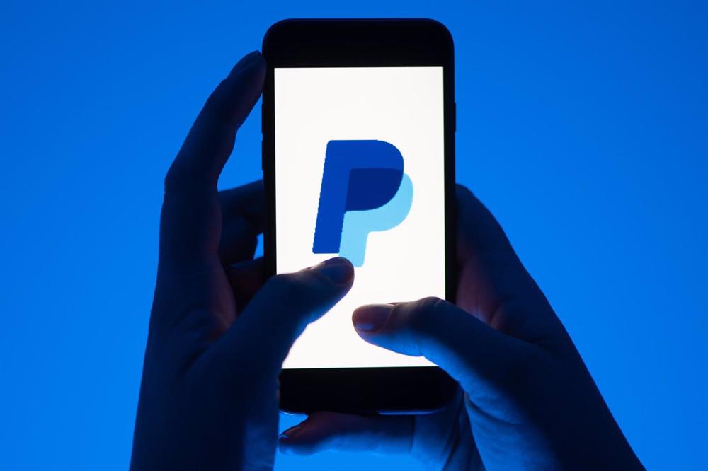 Archivo - FILED - 12 May 2022, Saxony, Dresden: A woman holds a smartphone with the logo of the payment service Paypal. Germany's Federal Cartel Office announced on Monday that it has launched proceedings against the online payment service PayPal on suspi Archivo