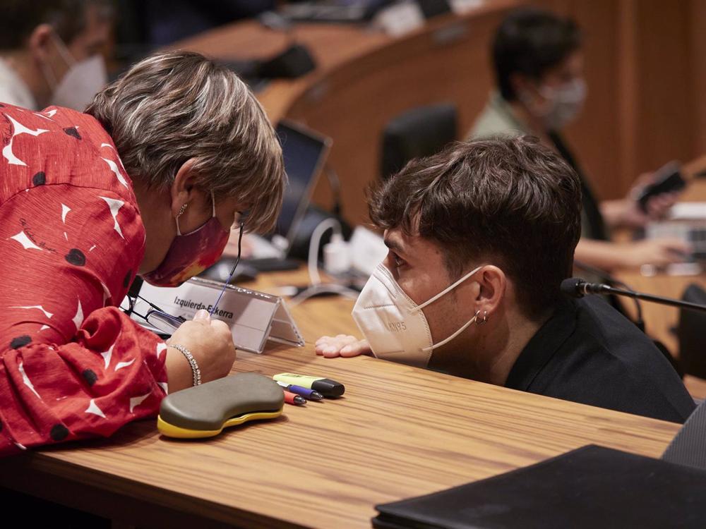 Archivo - El parlamentario de Geroa Bai Pablo Azcona habla con la parlamentaria de I-E Marisa de Simón en un pleno del Parlamento de Navarra. Archivo