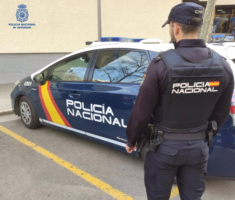 Archivo - Un agente de la Policía Nacional en Palma junto al coche policial. Archivo