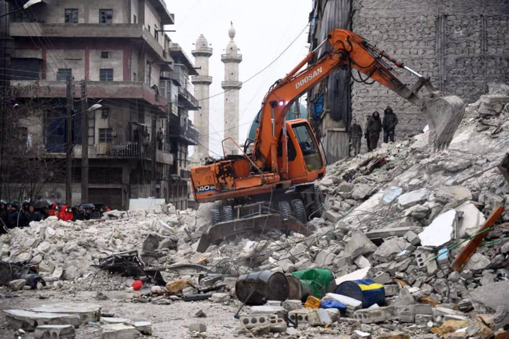 Operatori e volontari partecipano ai soccorsi tra le macerie di un edificio crollato ad Aleppo in seguito alle scosse di terremoto vicino al confine tra Turchia e Siria. Operatori
