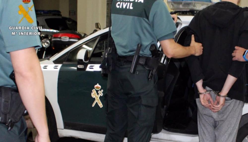 Un agente de la Guardia Civil acompaña a un detenido. Un
