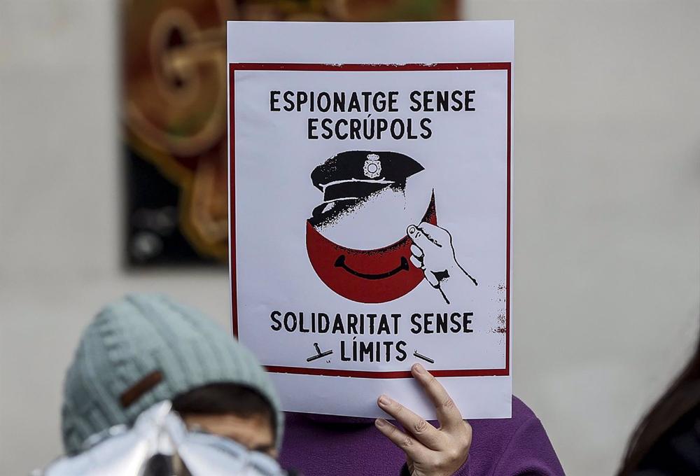 Una mujer sujeta un cartel que hace referencia al espionaje, durante una rueda de prensa de miembros de los movimientos vecinales CSOA l'Horta, Cuidem Benimaclet y Alerta Solidària. Una