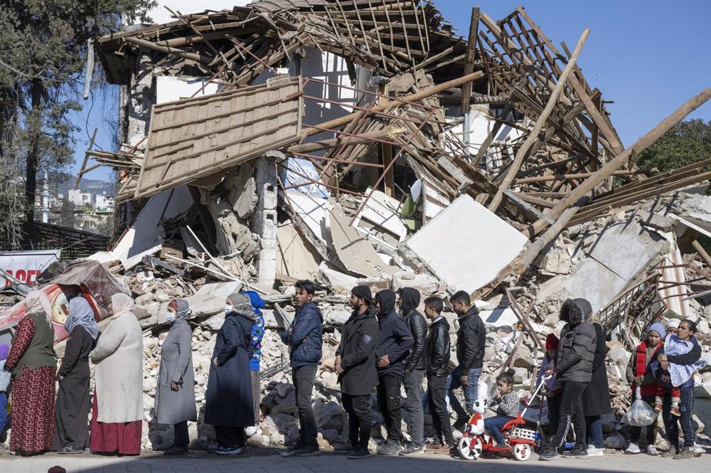 Un grupo de damnificados por los terremotos en Turquía hace cola para recibir ayuda alimentaria en la localidad de Kirikhan Un