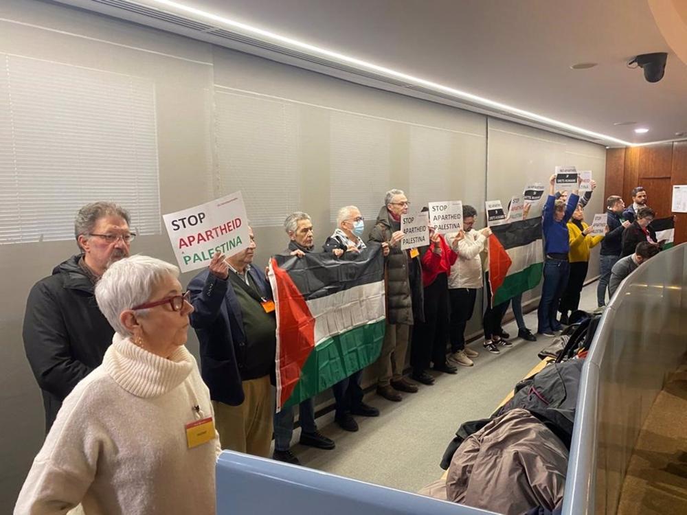 Impulsores de la iniciativa ciudadana se manifiestan durante la comisión con banderas palestinas y pancartas contra el 'apartheid'. Impulsores