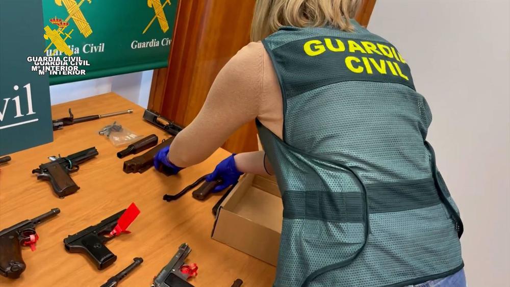 Una agente de la Guardia Civil con algunas de las armas intervenidas en la operación. Una