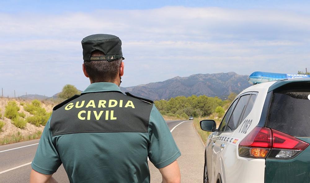 Archivo - Un agente de la Guardia Civil junto a un vehículo en una carretera. (Foto de archivo). Archivo